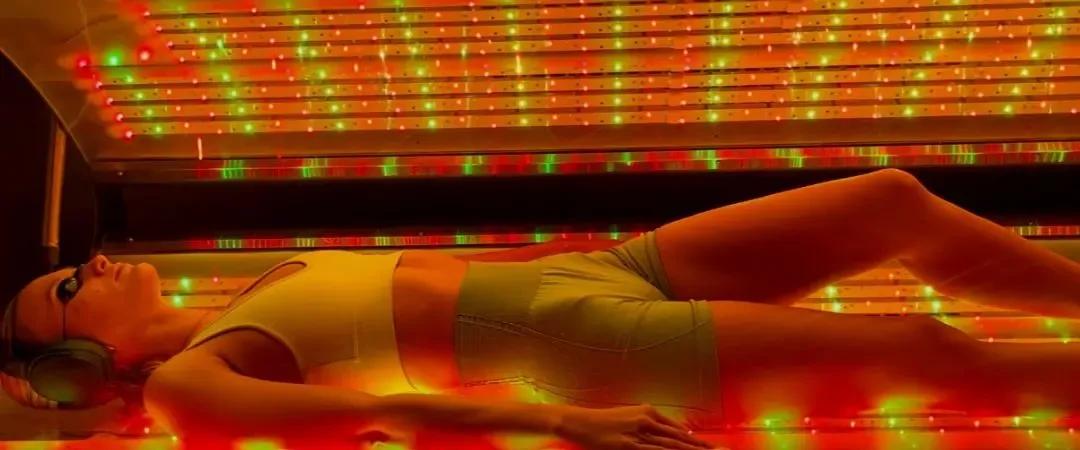 A patient lying inside the lit ARRC Elysium during a whole-body red light session